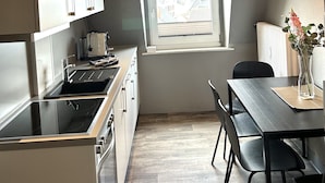 Una cocina compacta con ventana, un comedor con sillas y un radiador.