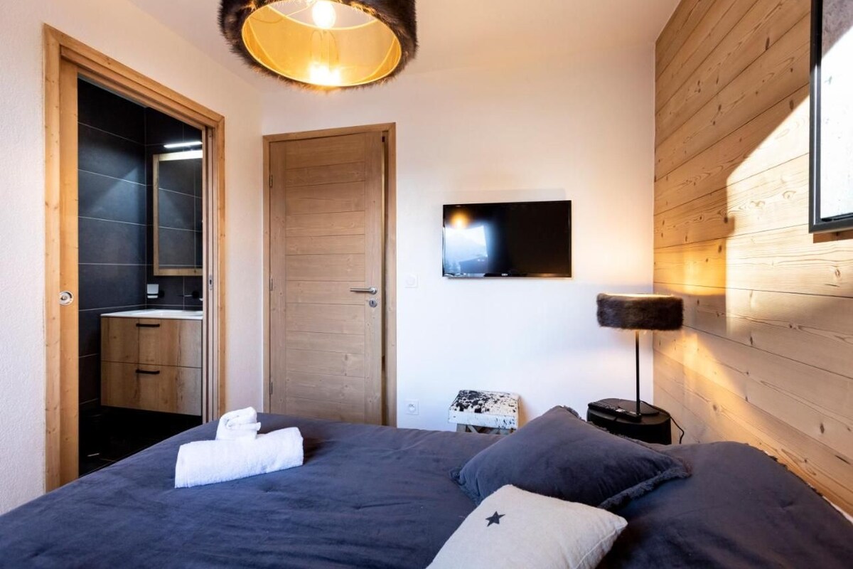 Une chambre à coucher avec un lit, une télévision, une porte en bois et une petite table.