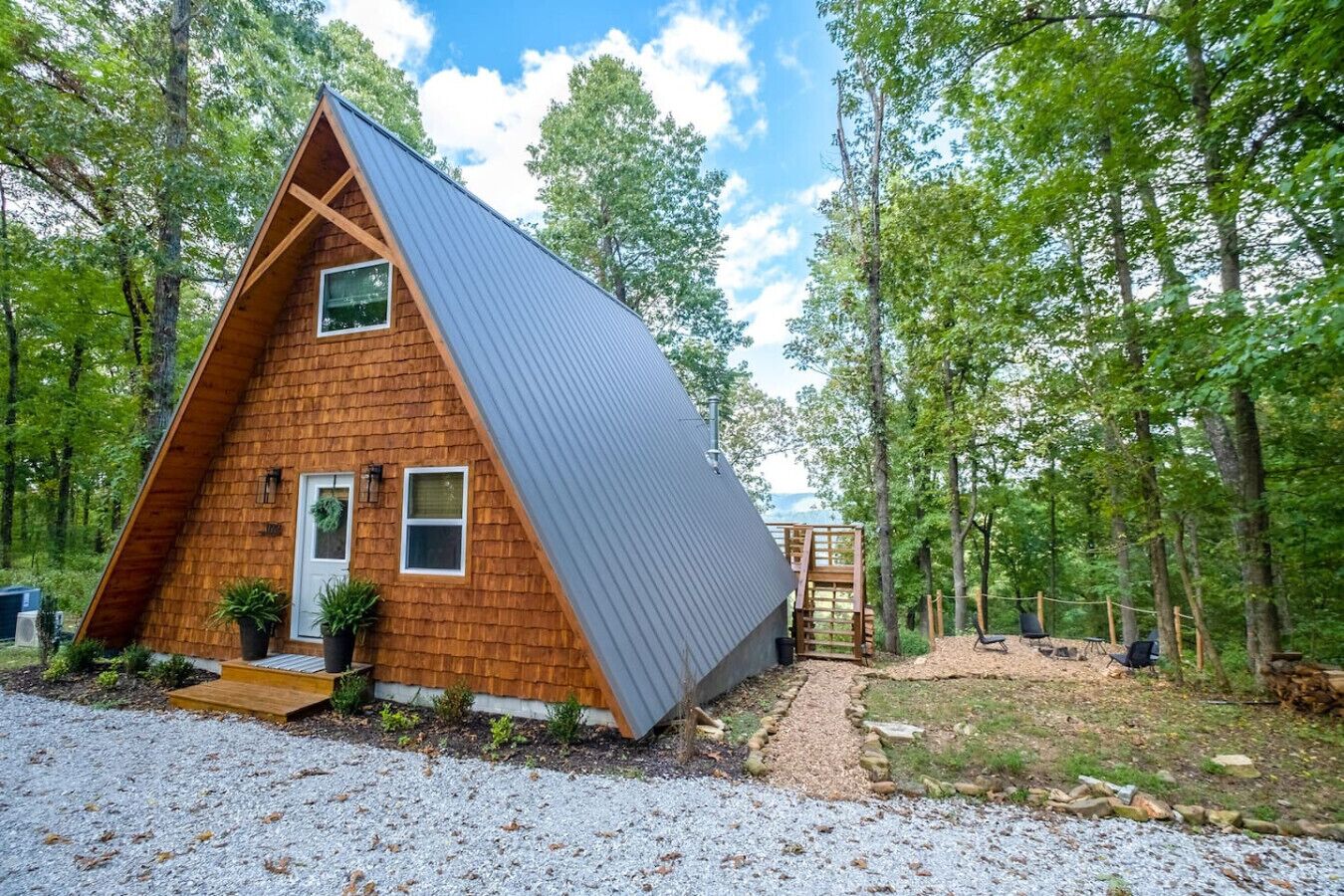 Une cabane en bois avec un toit en pente, un petit porche et une allée gravillonnée.