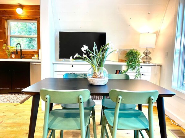 A dining area with a table and chairs, a TV, and a potted plant.