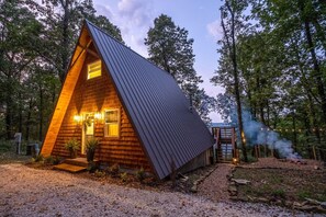 A wooden cabin with a sloped roof, a small porch, and a visible chimney emitting smoke.