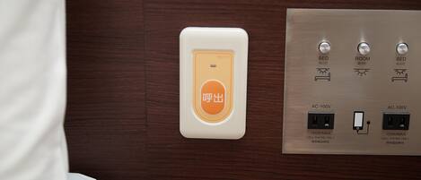 Panel eléctrico de una habitación de hotel con un botón de llamada y dos enchufes AC-100V, cada uno soportando un máximo de 150W para teléfonos móviles.