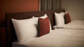 A hotel room with two beds, each with white linens and red patterned pillows.