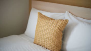A bed with a patterned pillow and a plain white pillow.