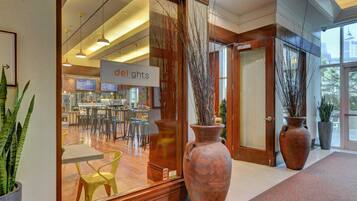 A modern interior with a reception area, large vases, and a dining area visible through the glass.