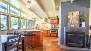 A spacious kitchen with a large island, wooden cabinets, and a fireplace. - Sparkling Clean Mid Century Modern Home in Ferry Street Bridge Area (Eugene)