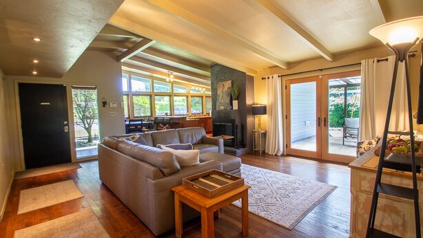 A spacious living room with a large sofa, a fireplace, and a view of the outdoors. - Sparkling Clean Mid Century Modern Home in Ferry Street Bridge Area (Eugene)