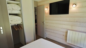 A bedroom with a bed, a wardrobe, a television mounted on the wall, and a radiator. - Arcs 1800: Renovated 3BR 🏔️ 4 Crystals + Parking Incl. 🚗 - Transarc 100m (Bourg-Saint-Maurice)
