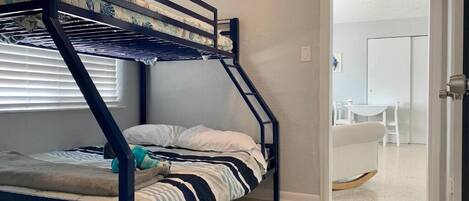 Una cama literera en una habitación con una puerta que da a un baño.