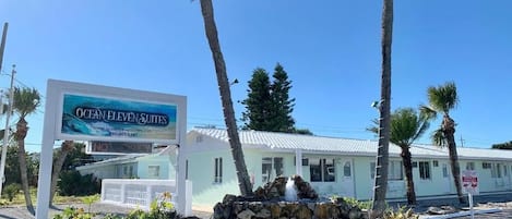 Une enseigne indiquant l’emplacement de l’hôtel Ocean Eleven Suites, avec une vue dégagée sur le bâtiment et les palmiers en arrière-plan.