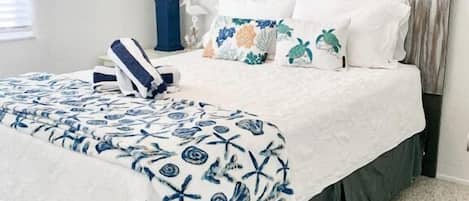 A bedroom with a bed, a nightstand, a lamp, and a wall art piece.