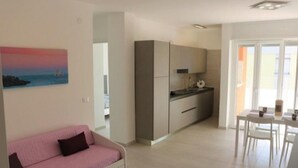 Un apartamento moderno con kitchenette, comedor y sala de estar con sofá rosa.