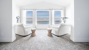 A modern room with a large window, two white armchairs, and a small table. - Luxurious Oregon Coast Townhouse with Mesmerizing Views! (Coos Bay)