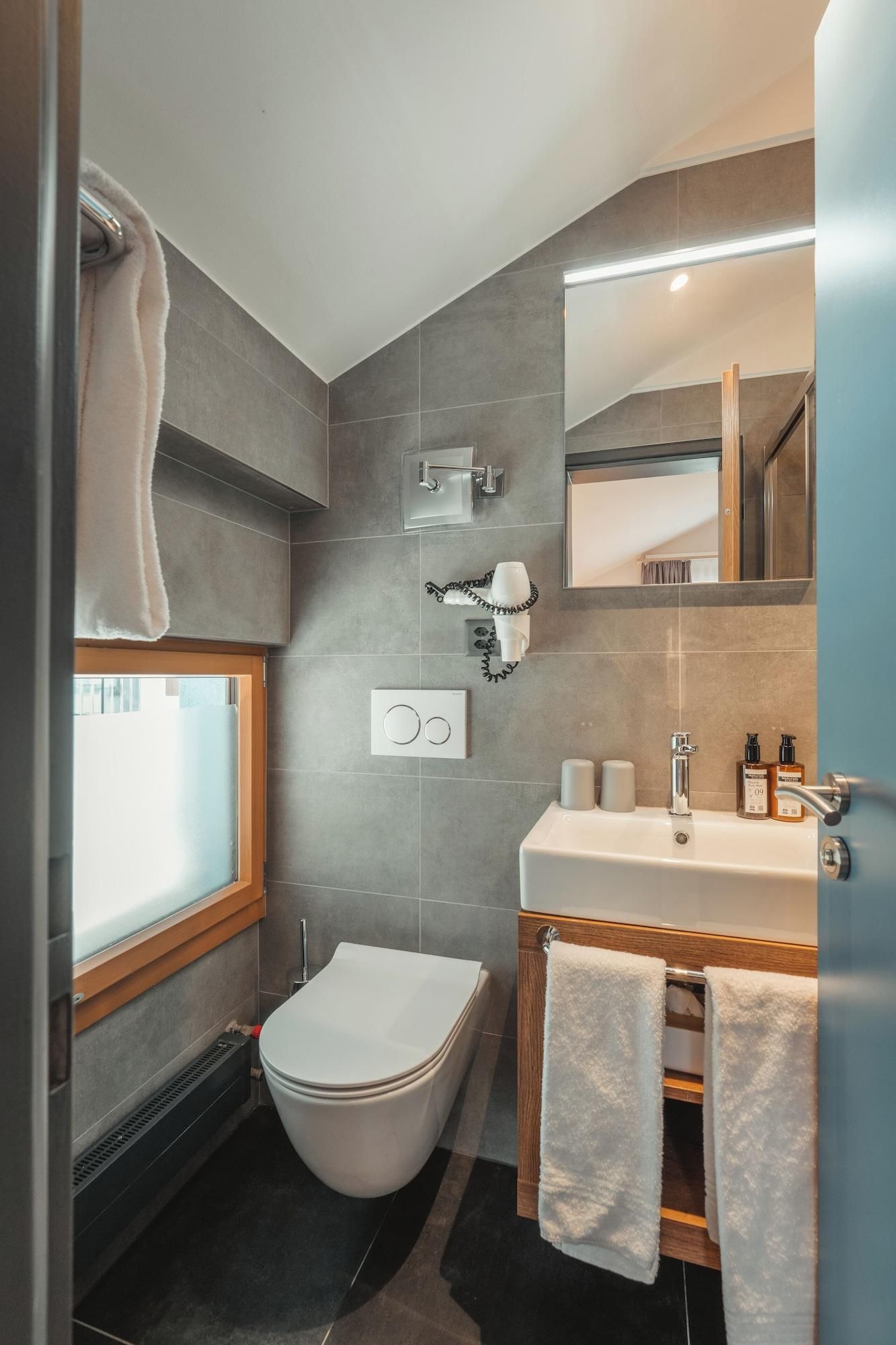 Un baño moderno con inodoro, bidé y lavamanos con espejo.