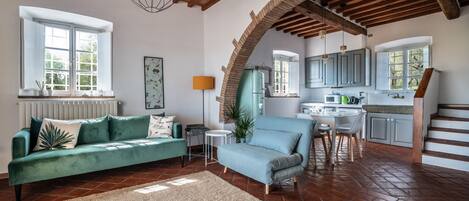 A spacious living area with a sofa, a dining table, and a kitchen in the background.
