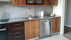 Una cocina con encimeras de granito, electrodomésticos de acero inoxidable, armarios de madera y lavavajillas.