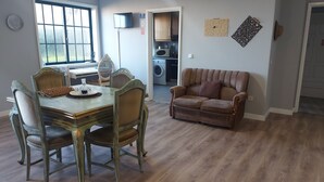 Un comedor con una mesa y sillas de madera, un sofá y una cocina al fondo.