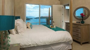 Un dormitorio con una cama grande, un aparador, un espejo y vistas al mar.
