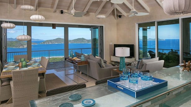 Amplia sala de estar con balcón con vistas al mar, amueblada con sofá, mesa de centro y mesa de comedor.