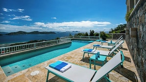 Una piscina infinita con sillones de descanso y vistas al mar.