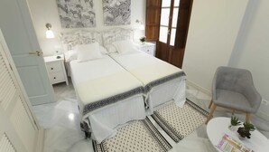 Un dormitorio con cama doble, una mesita de noche, una silla y dos obras de arte en las paredes.