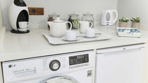 Una cocina moderna con cafetera, juego de té y lavadora.