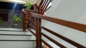 A wooden staircase with a handrail, leading to a landing with a potted plant.