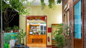 A reception area with a wooden desk, potted plants, and a sign indicating a homestay.