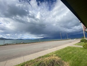 Eine Straße mit einer Grünfläche und einem Gewässer im Hintergrund.
