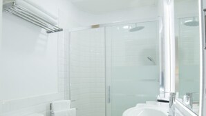 Un baño moderno con inodoro, lavamanos y cabina de ducha de vidrio.
