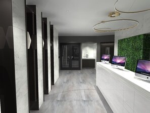 A modern reception area with a white reception desk, multiple monitors, and a green wall. - Lusso (Macclesfield)