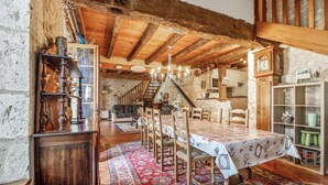 Un coin repas rustique, avec des chaises en bois et une table dressée pour six personnes, le tout entouré d’un tapis à motifs.