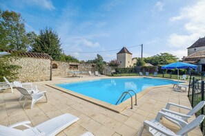 A swimming pool with white lounge chairs and a stone wall. - Homerez - House in Thenac (Thenac)