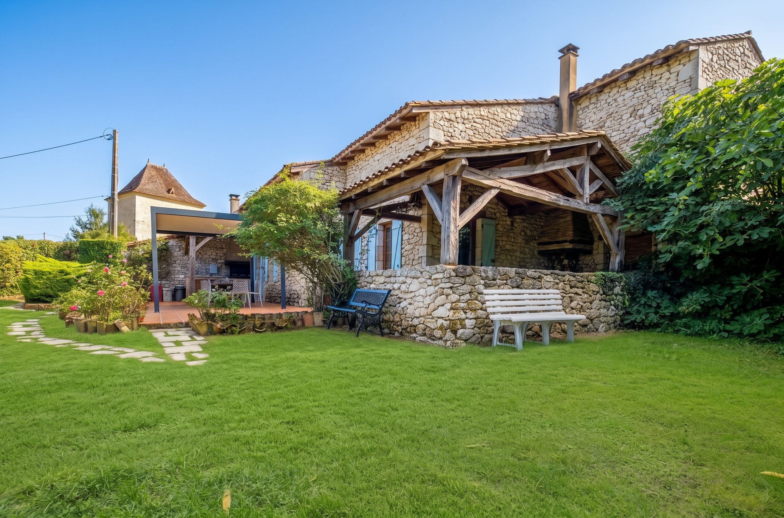 A stone house with a covered patio and a lawn.