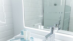 A bathroom with a white sink, a mirror, and a glass shower enclosure. - GR Suites Boutique Catedral AP-B (Málaga)
