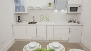 A modern kitchen with white cabinetry, a built-in microwave, and a coffee machine. - GR Suites Boutique Catedral AP-B (Málaga)
