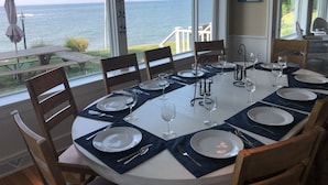En matplats med utsikt över havet, ett bord dukat för sex personer och en skylt på väggen.