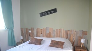 Een net opgemaakt bed met twee kussens, een houten hoofdbord en een bordje erboven.