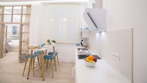 Una cocina moderna con comedor, armarios blancos y una ventana con persianas.
