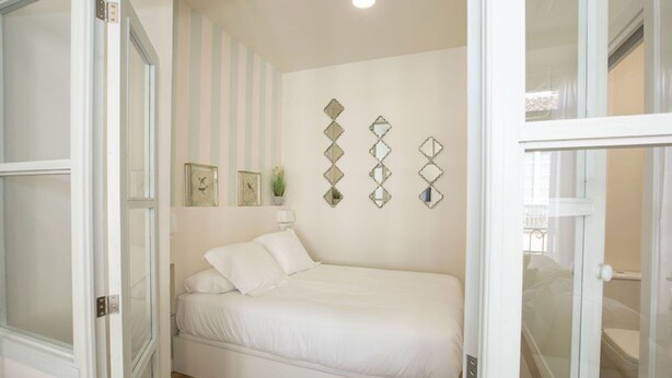 Une chambre à coucher avec un lit, un miroir fixé au mur et une porte.