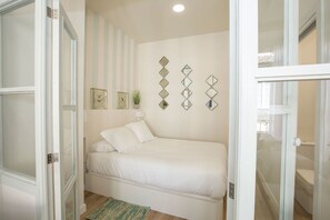 Une chambre à coucher avec un lit, un miroir fixé au mur et une porte.