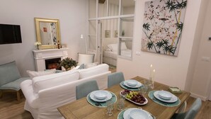 Un coin repas avec une table en bois dressée pour quatre personnes, entourée d’un canapé et de chaises blancs.
