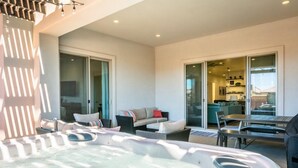 A modern indoor pool area with a hot tub, seating area, and a view of the adjacent kitchen and living space.