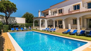A swimming pool with blue lounge chairs, a white building with arches, and a clear blue sky. - Jadlyn Yellow Villa, Falésia Beach, Albufeira, AC, WiFi, Swimming Pool !New! (Albufeira)