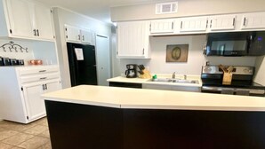 Una cocina moderna con armarios blancos, un refrigerador negro, un microondas y una estufa.