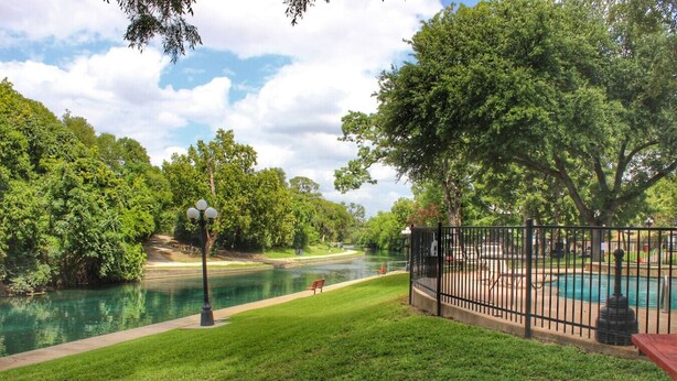 Un parque con un río, una piscina y una banca.