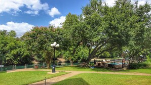 Un parque con piscina, un pabellón y un árbol grande.