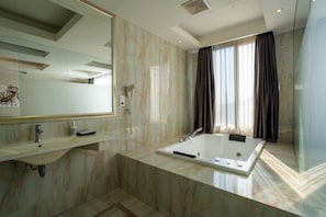 A modern bathroom with a large mirror, a bathtub, and a vanity with a sink.