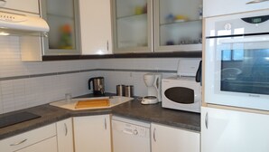 Une cuisine avec des meubles blancs, une machine à café, un four à micro-ondes et un lave-vaisselle.