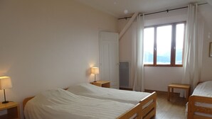 Une chambre à coucher avec un grand lit, deux tables de chevet, une fenêtre avec des rideaux et un radiateur.
